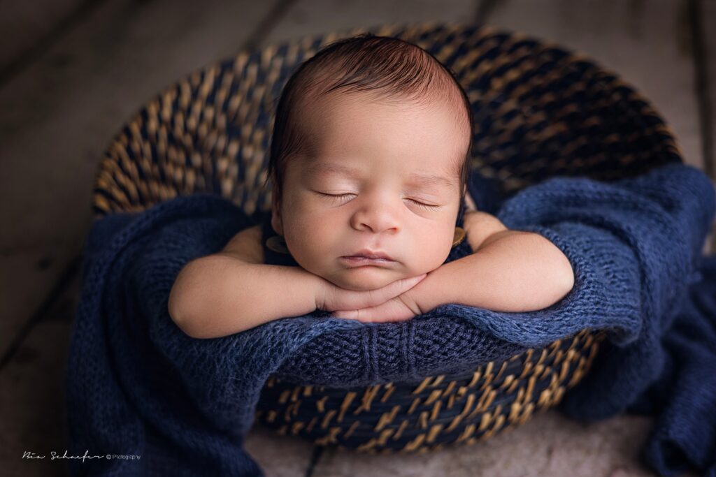 baby posing inside a blue basket